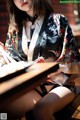 A woman in a black and white kimono sitting at a table.