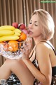 A woman sitting on a bed holding a bowl of fruit.