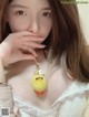 a woman wearing a white dress holding a yellow bird keychain