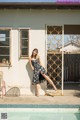 A woman leaning against a wall next to a swimming pool.