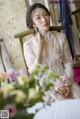 A woman in a white dress sitting on a chair.