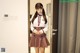 A woman in a school uniform standing in front of a door.