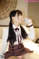 A woman in a school uniform drinking water from a bottle.