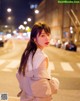 A woman standing in the middle of a city street at night.