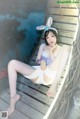 A woman in bunny ears sitting on a wooden bench.