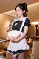 A woman in a maid outfit holding a bowl and a whisk.