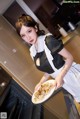 A woman holding a plate of food in a kitchen.