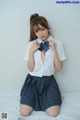 A woman in a school uniform is posing on a bed.