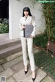 A woman in a white suit holding a book.