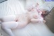 A woman in a pink and white outfit laying on a bed.