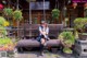 A woman sitting on a wooden bench in front of a building.