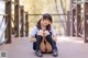 A woman in a school uniform sitting on a bridge.