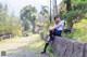 A woman sitting on a stone wall in a park.