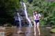 A woman in a sailor outfit standing in front of a waterfall.