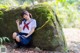 A woman in a school uniform sitting on a rock.