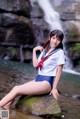 A woman in a sailor outfit sitting on a rock in the water.