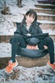 A woman sitting on a wooden bench in the snow.