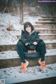 A woman sitting on some steps in the snow.