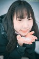 A young woman holding a handful of snow in her hands.