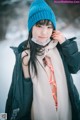 A woman wearing a blue hat and scarf in the snow.