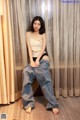 A woman sitting on a chair in front of a curtain.