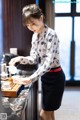 A woman pouring tea into a cup on a table.