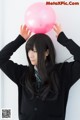 A young woman holding a pink balloon over her head.