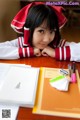 A woman sitting at a table with a book and pen.