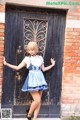 A woman in a blue and white dress standing in front of a door.