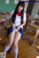 A woman in a school uniform is sitting on a desk.