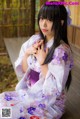 A woman in a kimono sitting on a wooden floor.