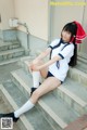 A woman in a school uniform sitting on some steps.