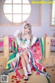 A woman in a kimono sitting on a bed in a room.