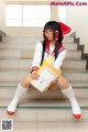 A woman in a school uniform sitting on the steps of a building.