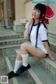 A woman in a white shirt and black shorts sitting on some steps.