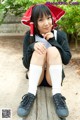 A young woman sitting on a wooden bench wearing a red hat.