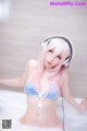 A woman in a bikini and headphones in a bathtub.