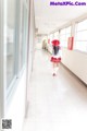 A woman in a school uniform walking down a long hallway.