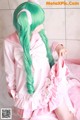 A woman with long green hair wearing a pink dress.