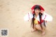 A woman in a red and white outfit on a beach.