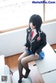 A woman in a school uniform sitting on a desk.