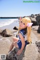 A woman in a sailor outfit sitting on a rock by the ocean.