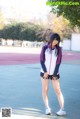 A woman standing on a tennis court with her hands on her hips.