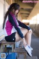 A woman sitting on a bench tying up her shoes.