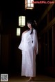 A woman in a white kimono standing in a room.