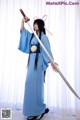 A woman in a blue kimono holding a sword.