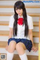 A young woman in a school uniform sitting on the stairs.