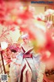 A woman in a kimono sitting under a cherry blossom tree.