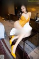 A woman in a yellow bodysuit sitting on a table.