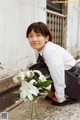 A young man kneeling down next to a vase of flowers.